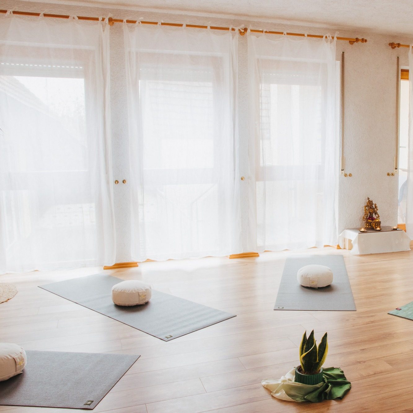 Helle, ruhige Yogastudio mit Matten, Kissen und Pflanzen.